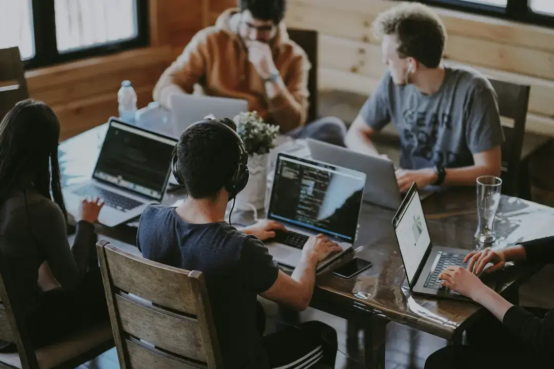 Teilnehmer:innen eines Data Science Bootcamps arbeiten gemeinsam an Laptops an Datensätzen und Machine‑Learning‑Modellen.